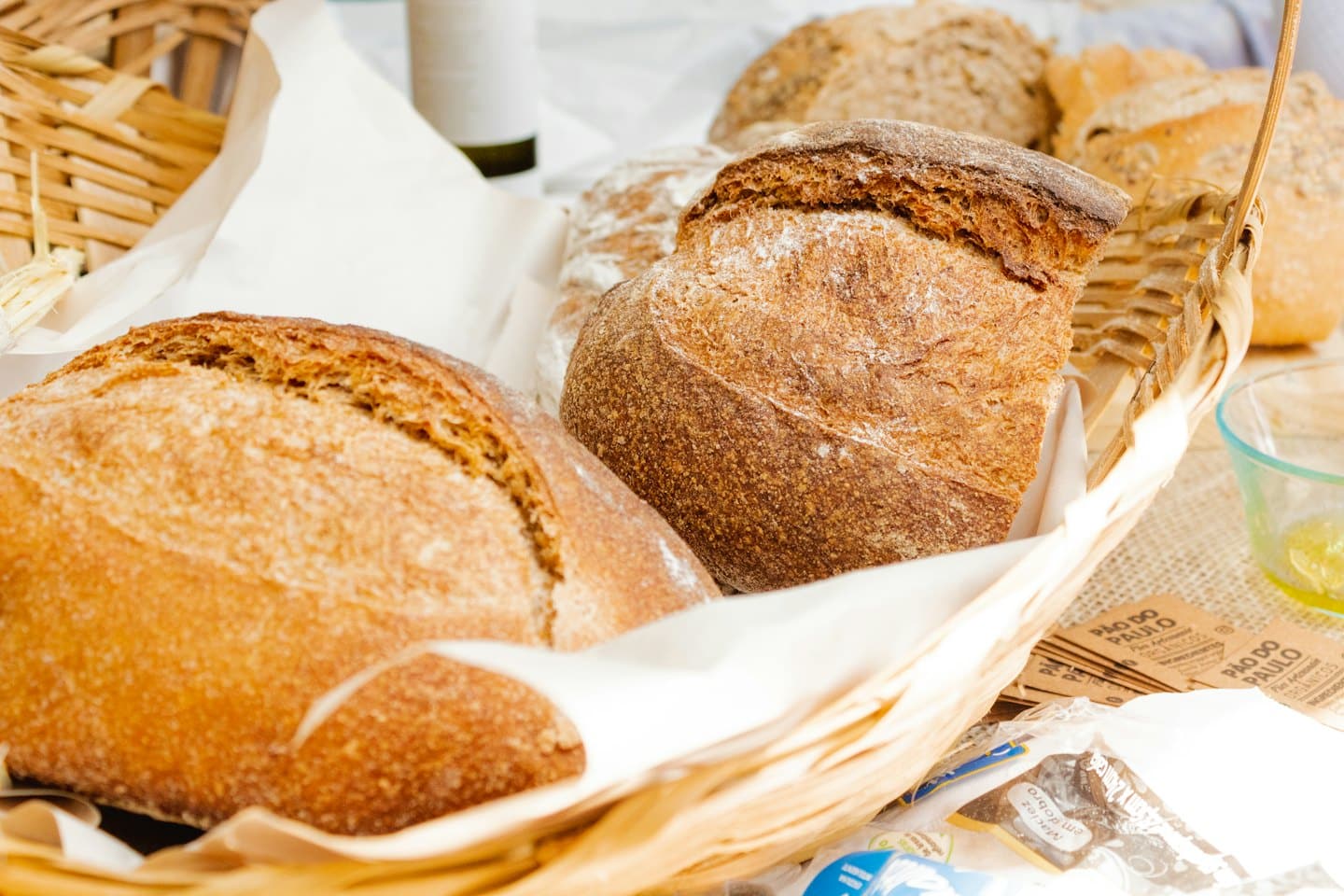 Rustic artisan bread loaves rest inside a woven wicker basket.